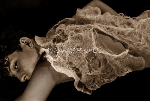 A woman laying on her stomach wearing a dress.