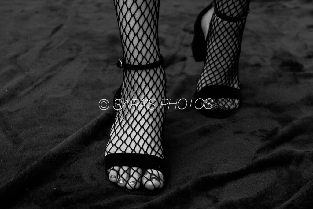 A woman 's feet in fishnet stockings and high heels.
