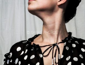 A woman with her eyes closed wearing a black and white polka dot shirt.