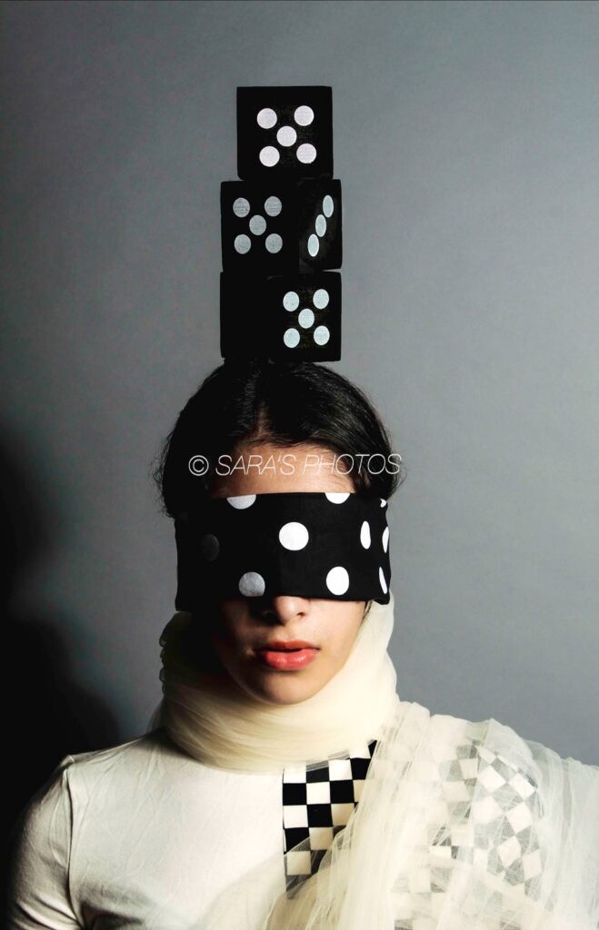 A woman with a blindfold and dice on her head.
