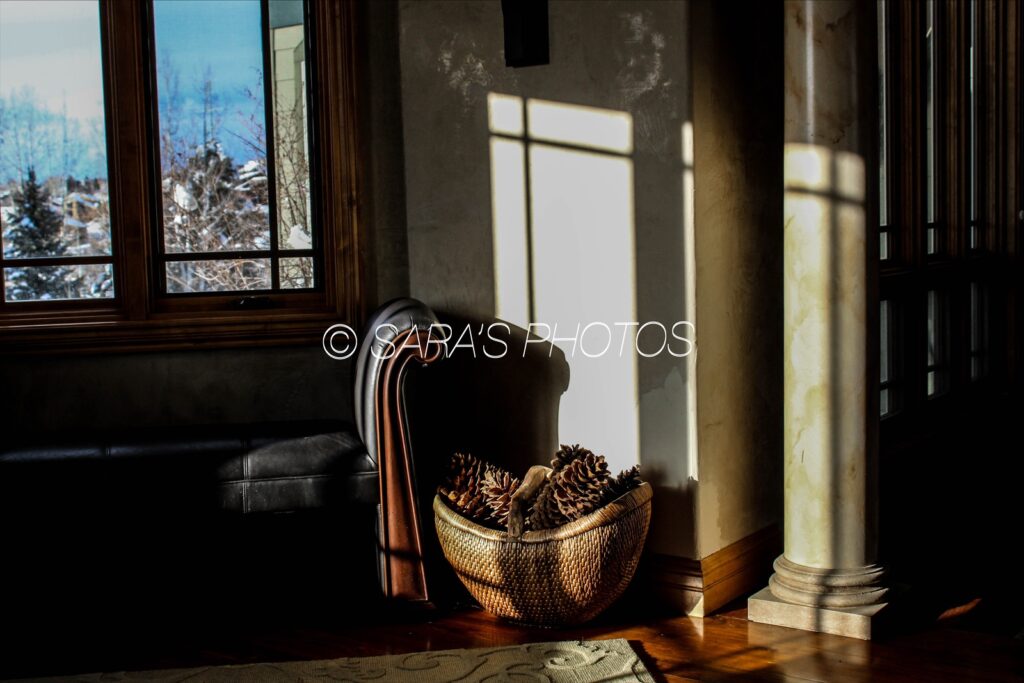 A chair and basket in front of a window.