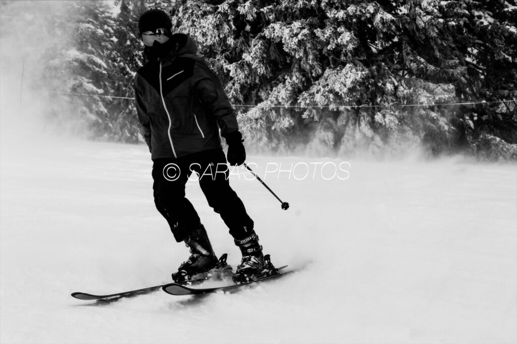 A man riding skis down the side of a snow covered slope.