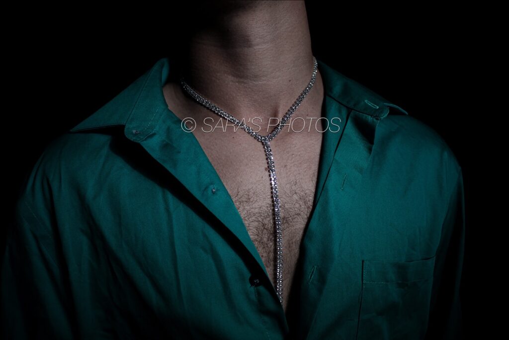A man wearing a green shirt and a necklace.