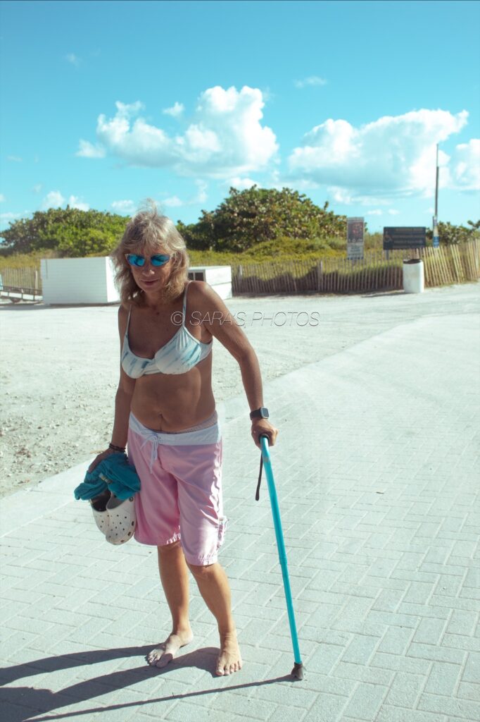 A woman in white bikini top and pink shorts holding onto a blue leash.